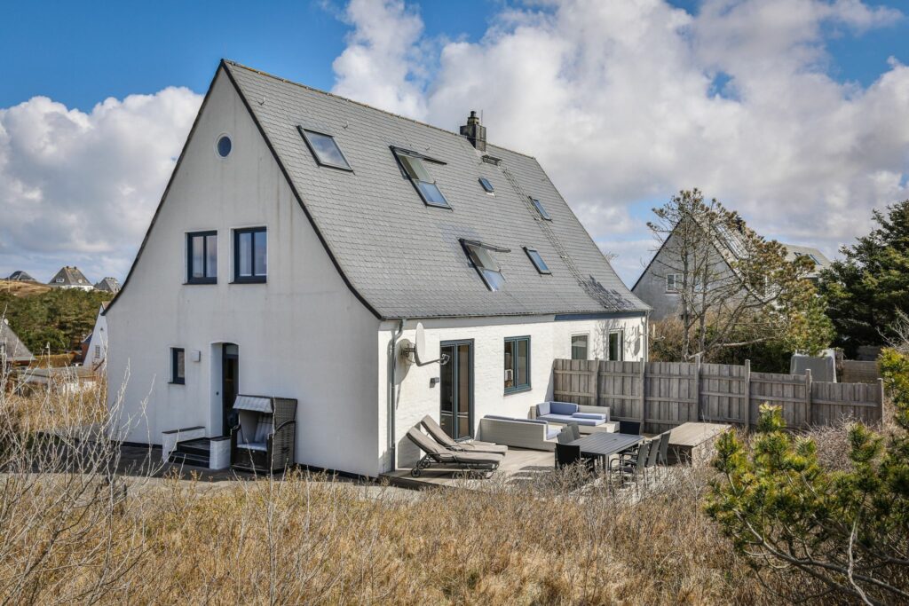 Ferienhaus mit Terrasse und Garten, einem Strandkorb und zwei Liegen.