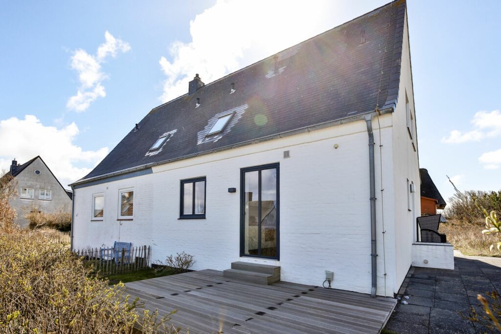 Großes Ferienhaus mit Terrasse bei Sonnenschein.