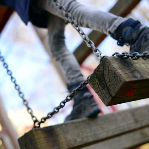 Ein Kind auf dem Spielplatz. es läuft über eine Holzbrücke.
