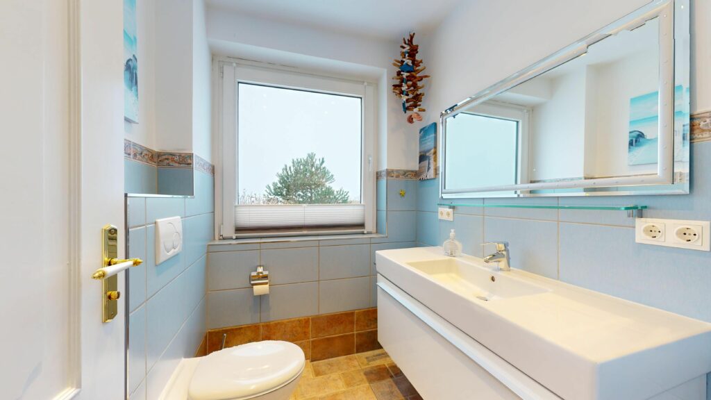 Badezimmer mit blauen Fliesen in Ferienwohnung Hörnum