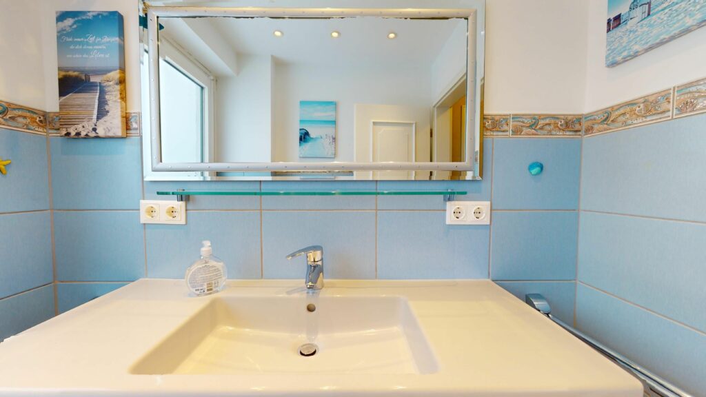 Badezimmer mit blauen Fliesen in Ferienwohnung Hörnum
