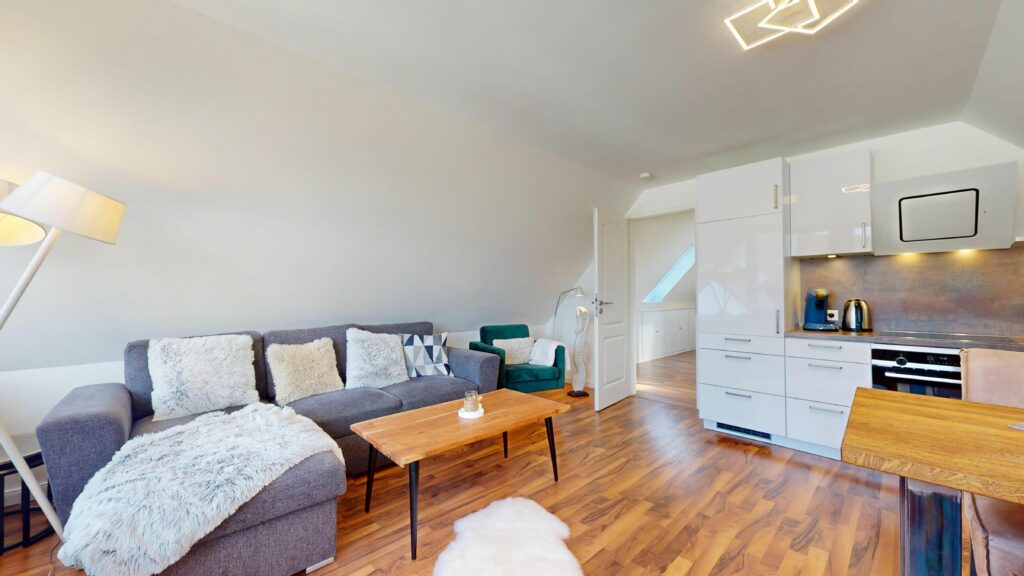 Offene Wohnküche mit grauem Sofa in Ferienwohnung Hörnum