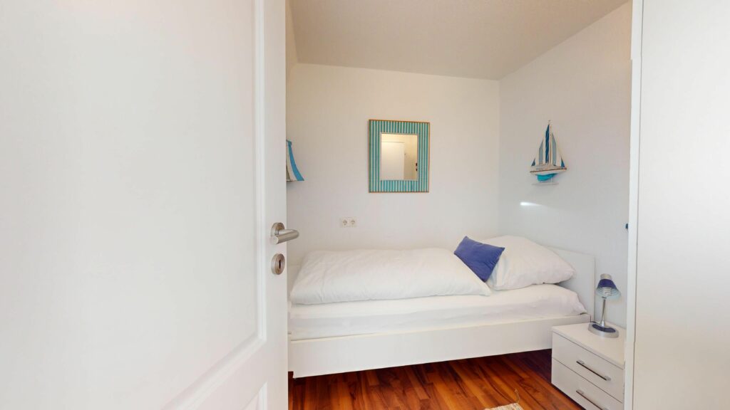 Schlafzimmer mit Einzelbett und maritimer Deko in Ferienwohnung Hörnum