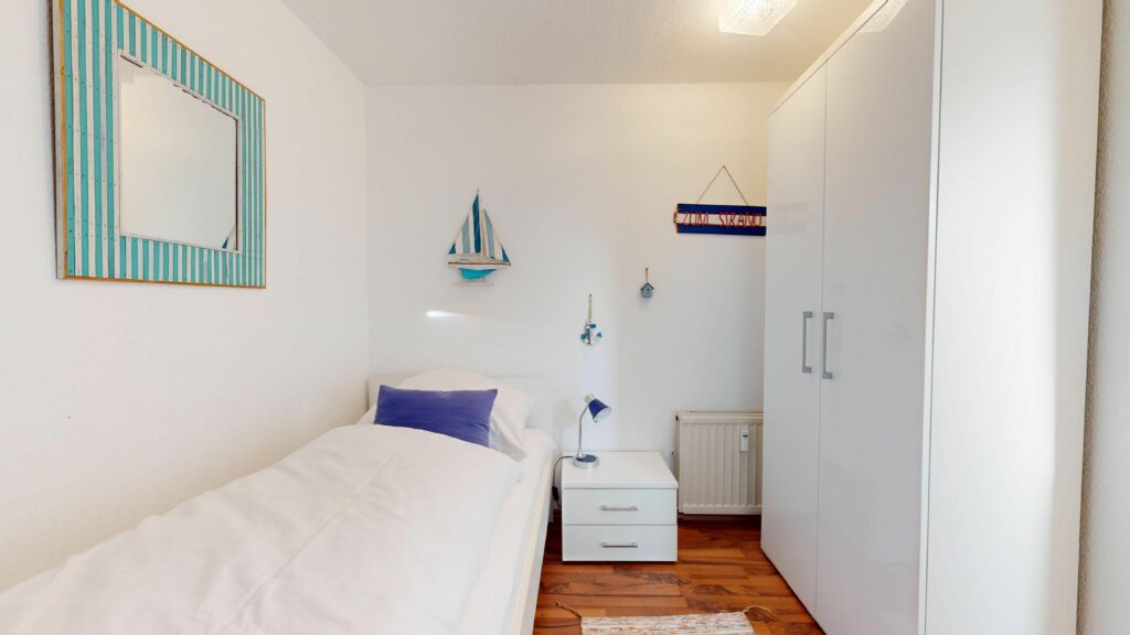Schlafzimmer mit Einzelbett und maritimer Deko in Ferienwohnung Hörnum