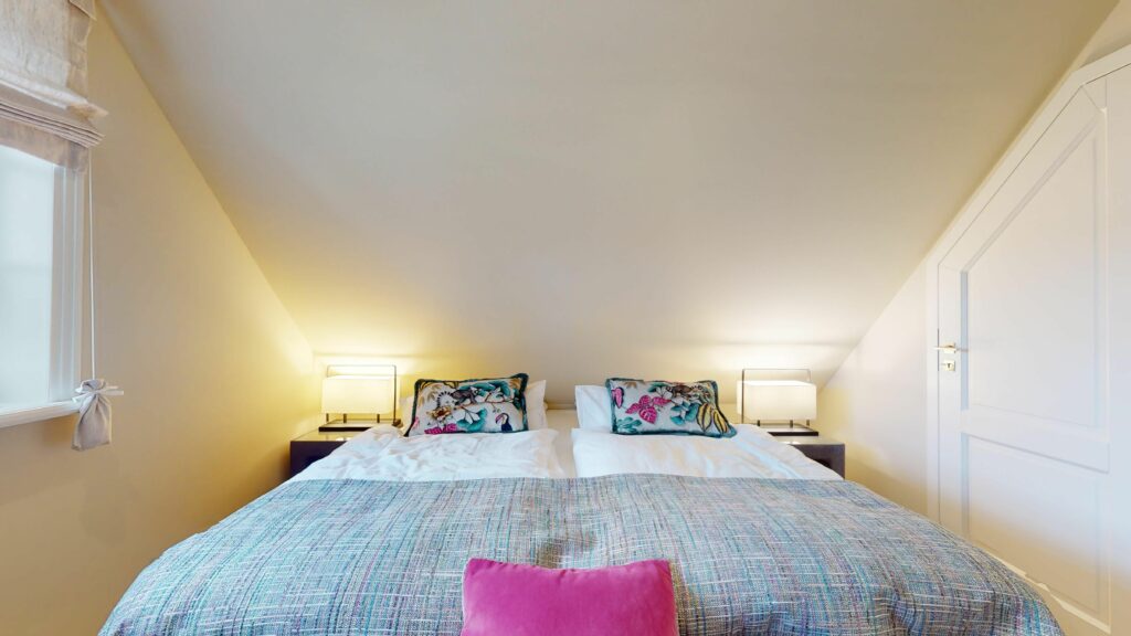 Schlafzimmer mit Doppelbett und bunten Kissen in Ferienwohnung Hörnum