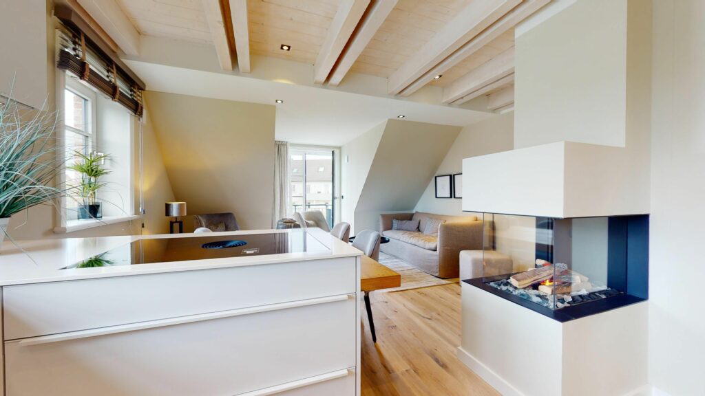 Offene Wohnküche mit Herdplatte mit integriertem Dunstabzug und Kamin in Ferienwohnung Hörnum