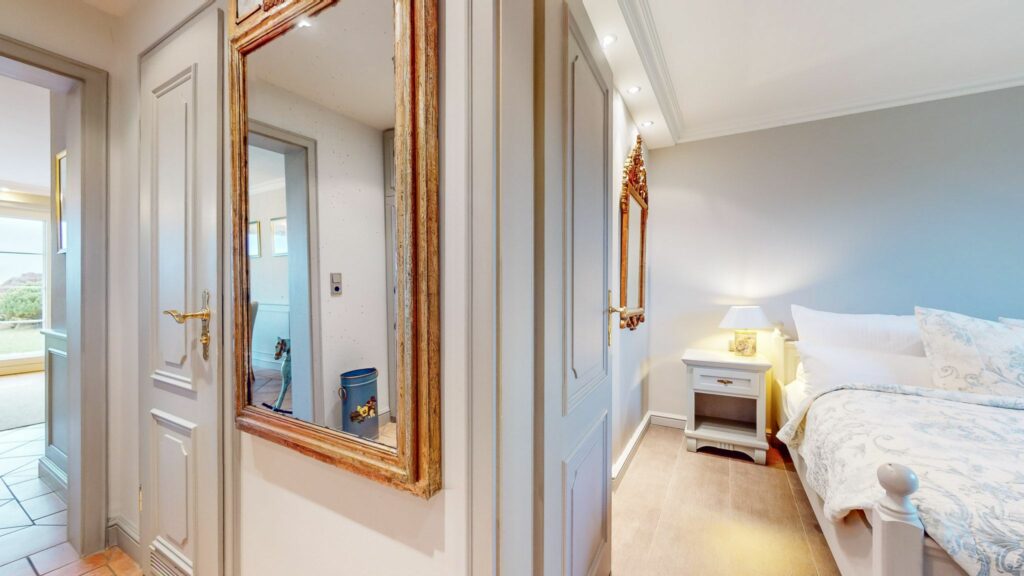 Schlafzimmer und Flur mit Spiegel in Ferienwohnung Hörnum