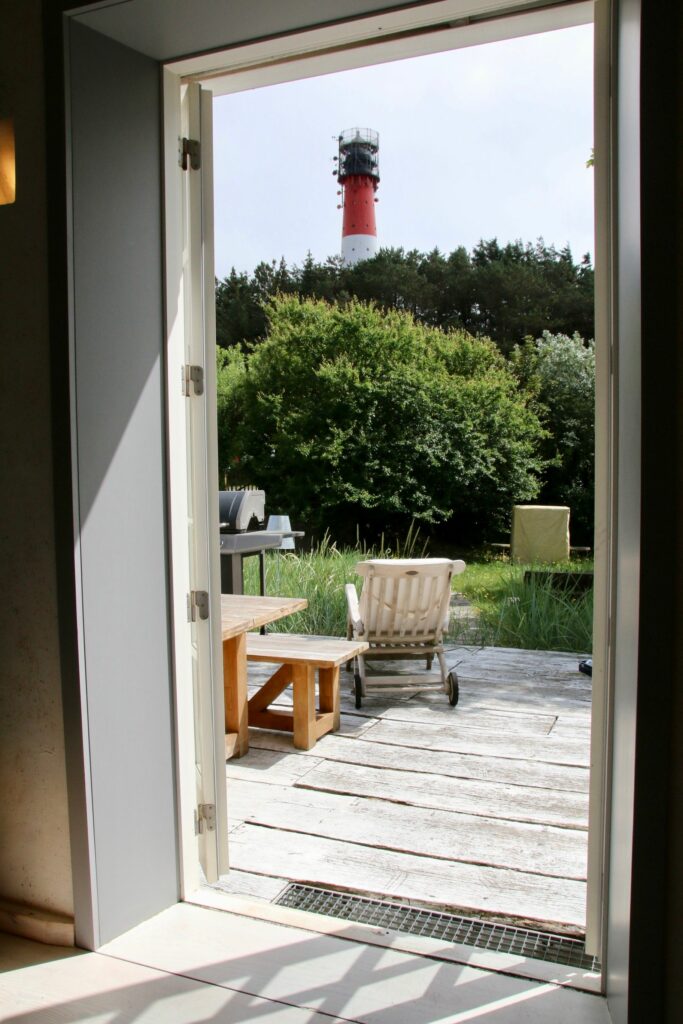 Blick aus der Ferienwohnung in Hörnum auf die Terrasse, dem grünem Garten und dem Leuchtturm