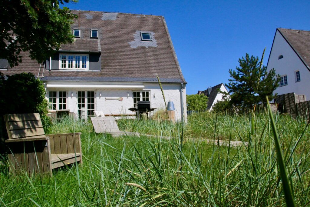 Grüner Garten und Holzstühle in Ferienwohnung Hörnum