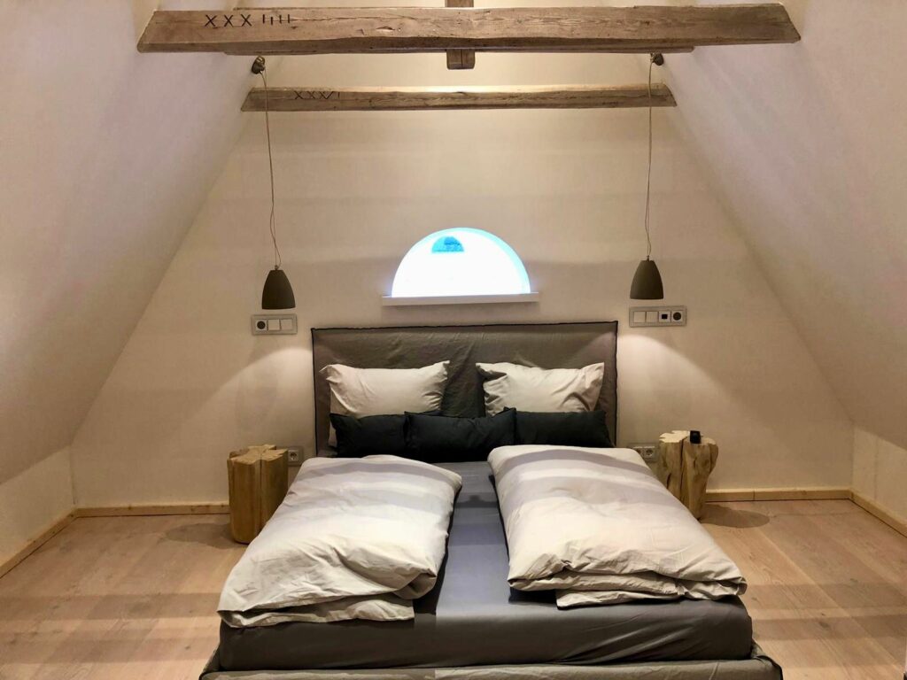 Schlafzimmer mit Doppelbett und hängenden Lampen in Ferienwohnung Hörnum