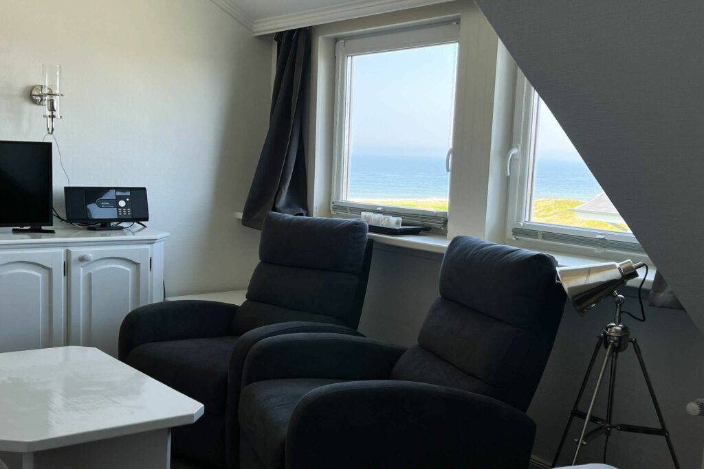 Sessel und Tisch vor Fenstern in Ferienwohnung auf Sylt