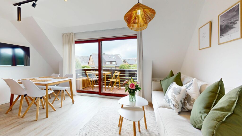 Sofa, Esstisch und Balkon in Ferienwohnung Hörnum