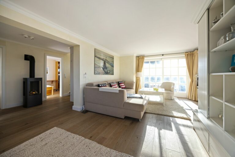 Wohnzimmer mit Kamin und Sessel und Sofa und Regal in Ferienwohnung auf Sylt